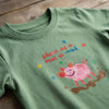 Close-up detail of pig-mud illustration on green t-shirt