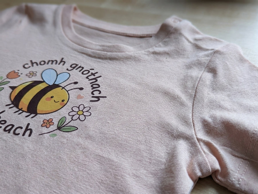 Close-up detail of bee illustration on peach t-shirt