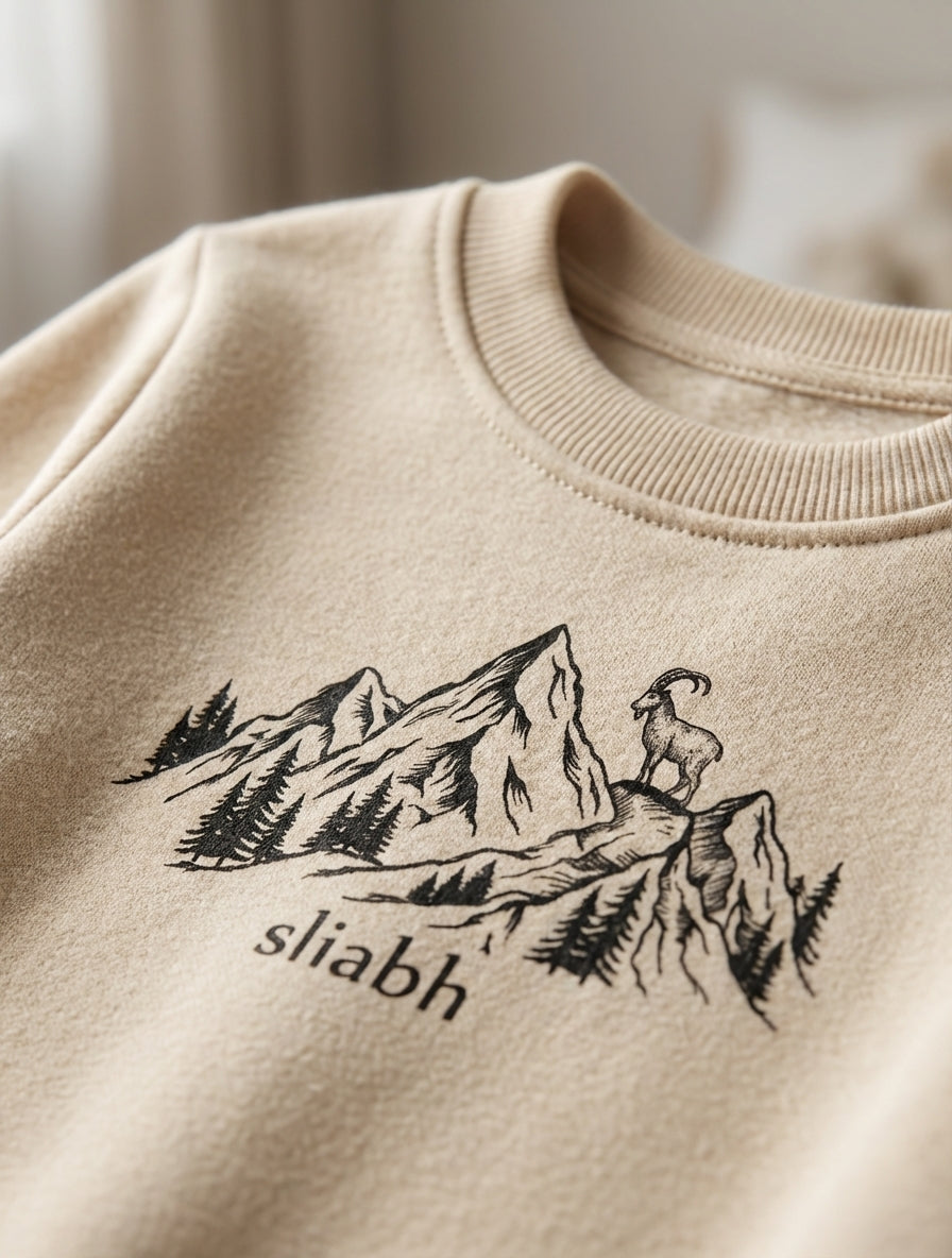 Close-up detail of mountain illustration on beige sweatshirt