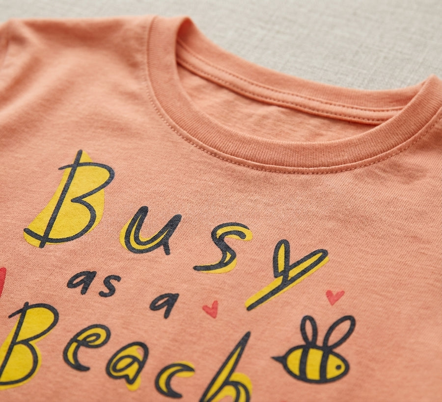 Close-up detail of bee illustration on peach t-shirt