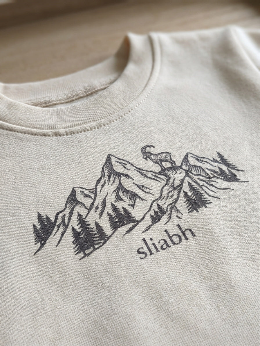 Close-up detail of mountain illustration on beige sweatshirt