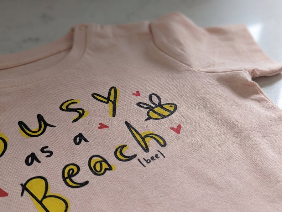 peach Baby Creator t-shirt with bee design — close-up detail of the print