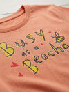Close-up detail of bee illustration on peach t-shirt